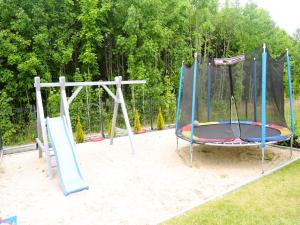 a playground with two swings and a trampoline at New, large holiday home for 10 people in Kołczewo