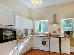 Una cocina con gabinetes blancos y lavadora. en 1 Bed in PENMAENMAWR 95495, en Penmaen-mawr