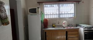 a small kitchen with a refrigerator and a sink at Oásis Flórida in Peruíbe