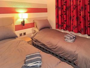 two beds in a room with red curtains at Forrest Lodge in Plumbland