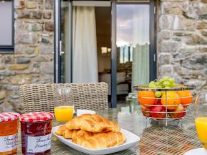 a table with a plate of croissants and a basket of fruit at 2 Bed in Cemaes Bay 77640 in Llanfechell