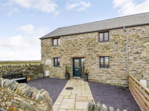 an old stone house with a stone wall at 2 Bed in Cemaes Bay 77640 in Llanfechell