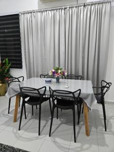 a dining room table with four chairs and a vase of flowers at Homestay DAR AL - HAQEM Full Aircond in Kuantan +18 photos