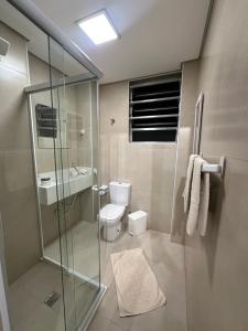 a bathroom with a toilet and a glass shower at Apartamento Studio pé na areia in Santos