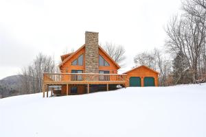 a wooden house with a deck in the snow at Perry Hill Escape in Waterbury