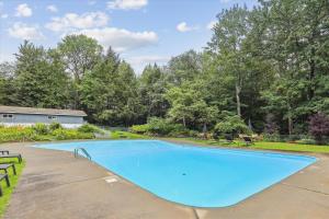 a large blue swimming pool in a yard with trees at Tollhouse 10B in Stowe Fork