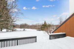a snow covered yard with a wooden fence and benches at Stonybrook 37 in Stowe