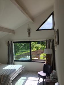 1 dormitorio con cama y ventana grande en B&B La Laiterie de Fontpatour, en Vérines