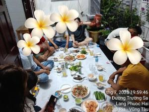 a group of people sitting around a table with food at Hiwinwin Homestay Holiday in Chợ Phước Hải