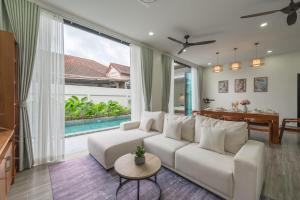 a living room with a white couch and a table at V226 4BR Pool Villa Near Laguna, Golf & Beaches in Laguna Phuket