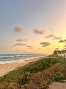 a beach with a fence and the ocean at Casa Perto da Praia - Barra de São Miguel in Barra de São Miguel