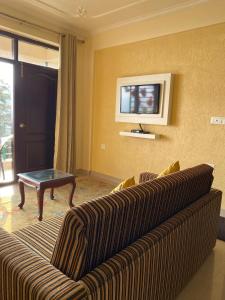 a living room with a couch and a tv at The Alpine Ramgarh in Rāmgarh