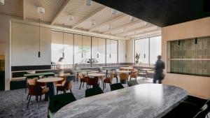 a cafeteria with tables and chairs and people in the background at Hyatt Place Whitehorse in Whitehorse