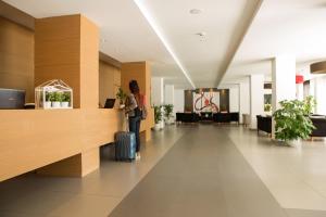 a woman standing in a lobby with a suitcase at Toscana Ambassador in Poggibonsi