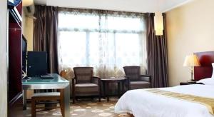 a hotel room with a bed and a desk and a window at Juntong Hotel in Bao'an