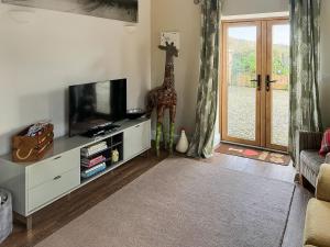 - un salon avec une télévision et une statue de girafe dans l'établissement Little Barn - Cottage, à Holsworthy