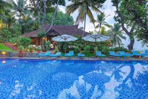 a swimming pool with blue chairs and umbrellas at Somatheeram Ayurveda village in Kovalam