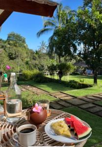 une table avec une assiette de nourriture et de la pastèque dessus dans l'établissement Waroeng Senaru cottage, à Senaru
