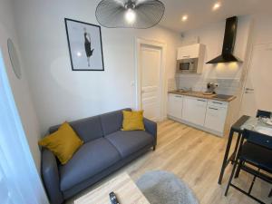 a living room with a blue couch and a kitchen at Logement Neuf Cosy avec Espaces Communs Premium 03 in Belfort