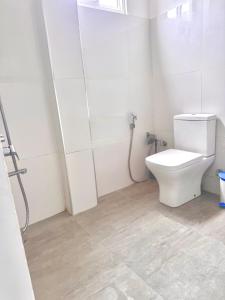 a white bathroom with a toilet and a shower at Coastal Cloud Backpackers in Unawatuna