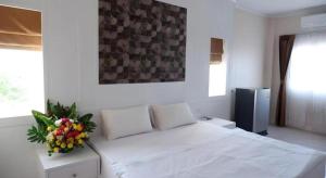 a bedroom with a white bed with a vase of flowers at Crystal Place Prathai in Prathai +22 photos