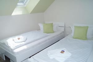 2 camas en una habitación blanca con almohadas verdes en REGIOHOTEL Pfälzer Hof Wernigerode, en Wernigerode