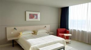 a bedroom with a large bed and a red chair at Jinjiang Inn Hengshui Anping in Anping