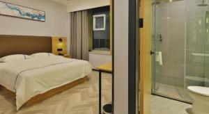 a bedroom with a bed and a bathroom with a shower at GreenTree Esports Hotel Qingdao Licang District Wanda in Qingdao +65 photos