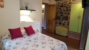 a bedroom with a large bed with red pillows at Apartamentos La Plazuela in Quintana de Soba