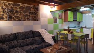 a living room with a couch and a table and a kitchen at Apartamentos La Plazuela in Quintana de Soba