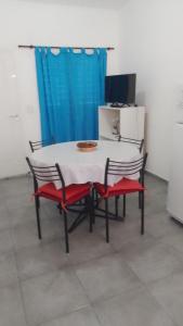 a table and chairs with a white table and a blue curtain at Departamento CR in Alta Gracia