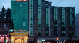 a tall building with a sign on top of it at Vienna Hotel Jiangxi Ji'an Jinggangshan in Jinggangshanzonghekenzhichang