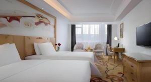 a hotel room with two beds and a flat screen tv at Vienna Hotel Guangdong Huizhou Huabianling Square in Huizhou +33 photos