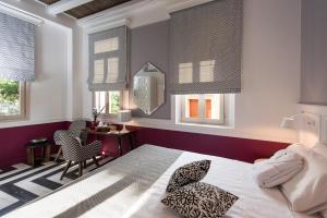 a bedroom with a bed and a chair and windows at Elia Portou Due in Chania Town