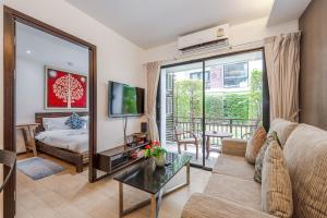 Una sala de estar con un sofá y un televisor. en C218 Cozy Condo Near Top Beaches in South Phuket, en Rawai Beach