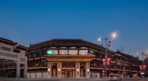 a building on the corner of a street at night at Vienna Hotel Guizhou Liupanshui Shuicheng Ancient Town in Shuicheng