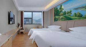 a hotel room with three beds and a painting on the wall at Vienna Hotel Zhuhai Huafashangdu Nanping Science Industrial Park in Nanping