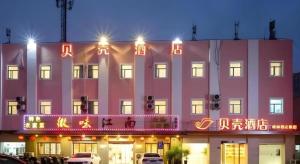 un gran edificio rosa con letreros de neón. en Shell Hotel Shnaghai Beiqiao Metro Station, en Shanghái