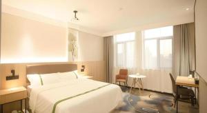 a bedroom with a large white bed and a window at GreenTree Inn Express Hefei City Bus Station in Feicheng