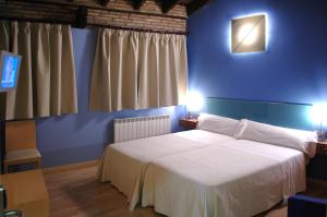 a bedroom with a white bed with a blue wall at La Merced de la Concordia in Tarazona de Aragón