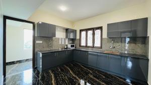 a kitchen with black cabinets and a black counter top at Away From Home - 8 - HomeStay, Entire 2 BHK Villa in Ooty