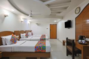 a hotel room with two beds and a television at The Ambassador in Vadodara