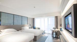 a hotel room with two beds and a flat screen tv at Echarm Hotel Leiyang in Leiyang