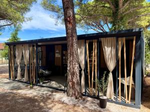 a black shed with curtains and a tree at TJ Escape - Mobile Home in Pakoštane