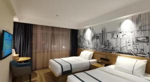 a hotel room with two beds and a tv at City Comfort Inn Suichuan County Government Pedestrian Street in Suichuan