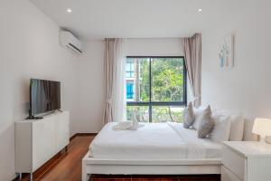 a white bedroom with a bed and a window at C219 1BR Island Hideaway 500m to Rawai Beach in Rawai Beach