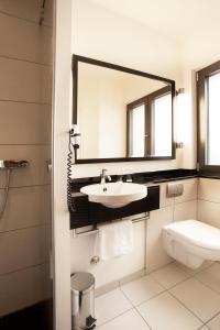 a bathroom with a sink and a mirror and a toilet at TOWNHOUSE Hotel in Frankfurt/Main +31 photos