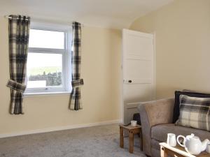 ein Wohnzimmer mit einer Couch und einem Fenster in der Unterkunft Benwells Holiday Cottage in Maud