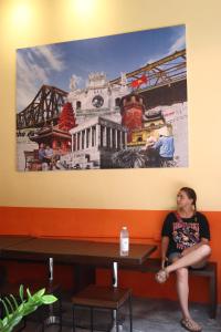 a woman sitting on a bench under a painting at Rebel Rooster Hostel in Hanoi +55 photos