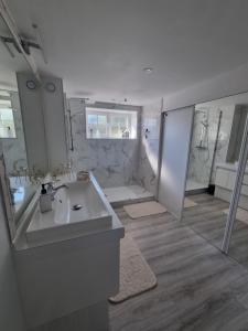 a white bathroom with a sink and a shower at La Villa Bellevue - 8 personnes avec piscine in Buissou +1 photo